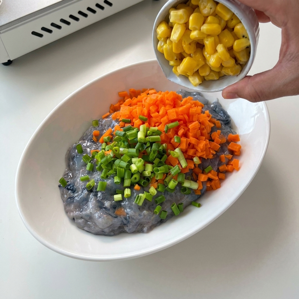 Chopped green scallions being added from a small white ramekin into a bowl of shrimp paste and diced carrots.