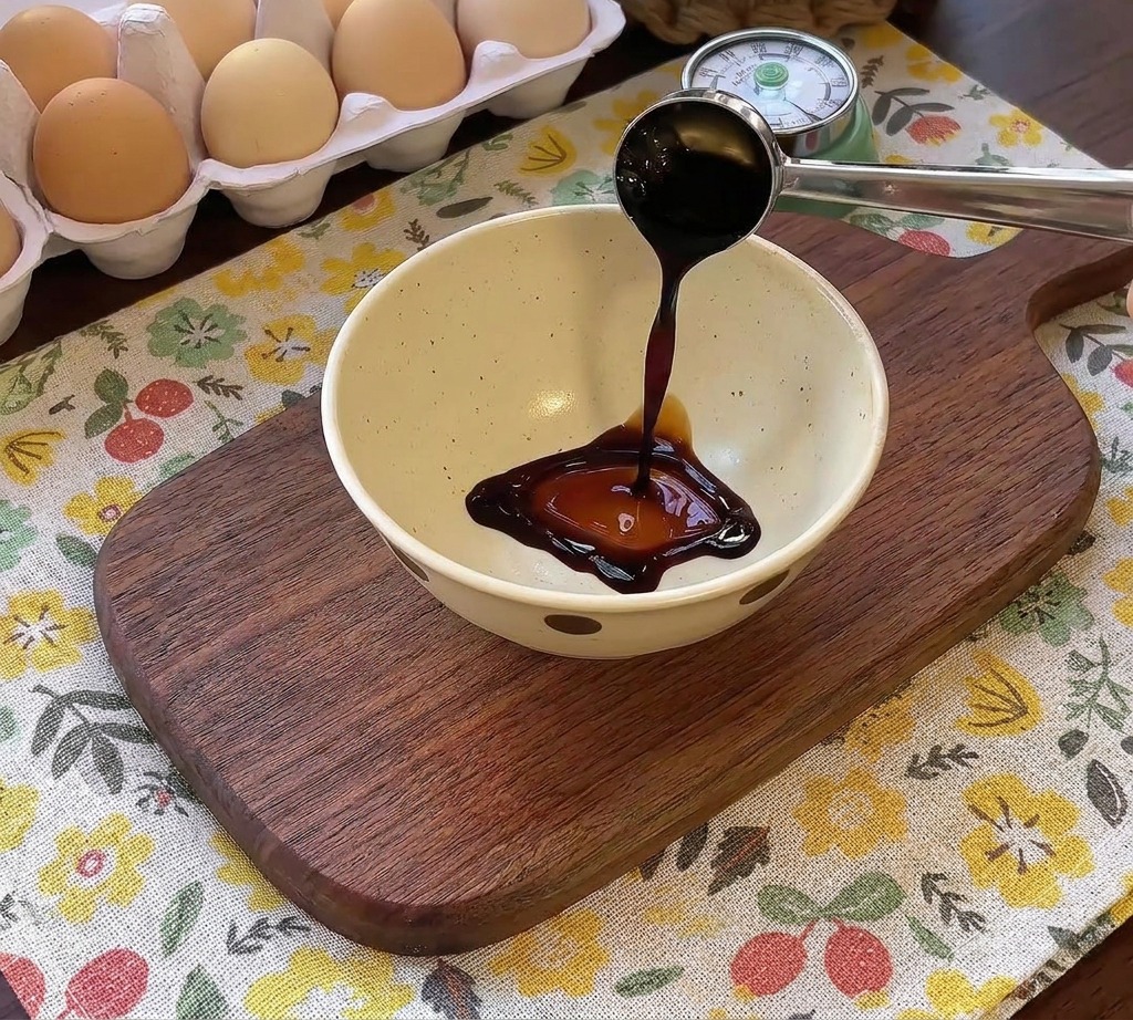 A dark savory sauce being poured into a bowl containing other condiments for a hamburger steak seasoning.