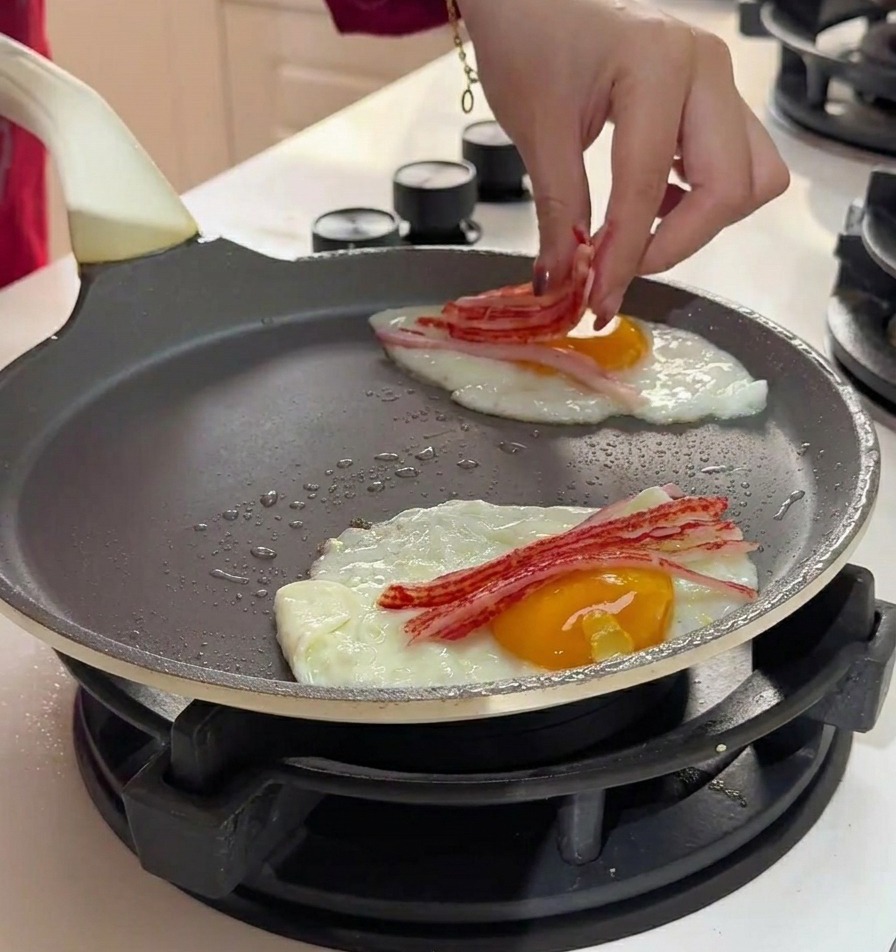 Hand placing thin strips of shredded crab meat onto eggs cooking in a pan.