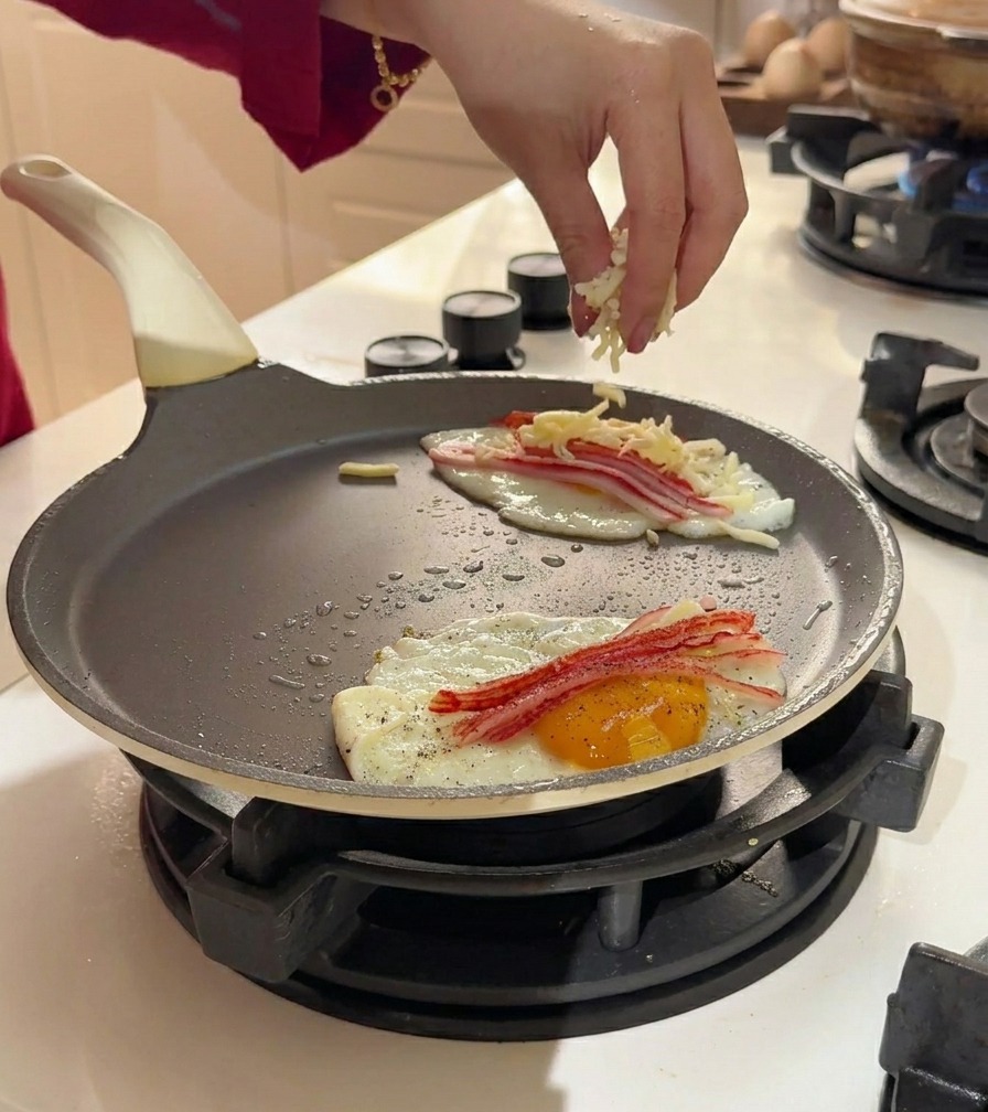 Shredded cheese being sprinkled over eggs and crab meat in a pan.