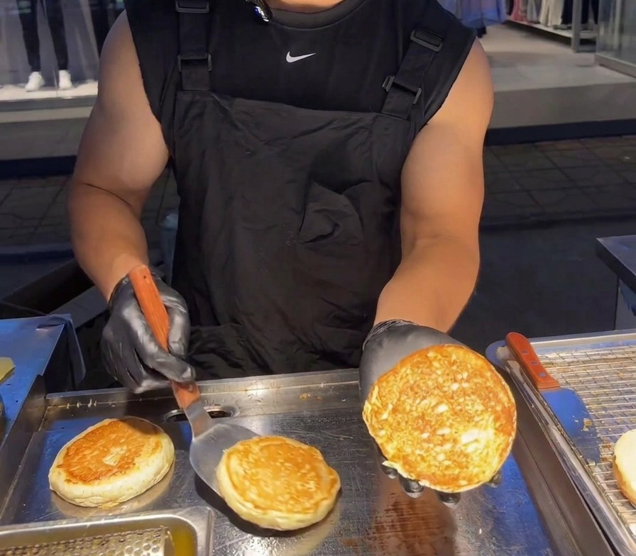 A person holding up a toasted burger bun half to show the crunchy, golden-brown seared surface.