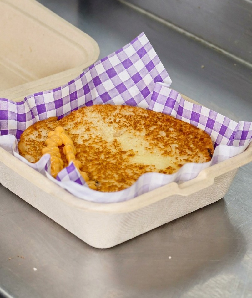 Creamy orange burger sauce drizzled in a zigzag pattern over a golden-brown toasted bun.