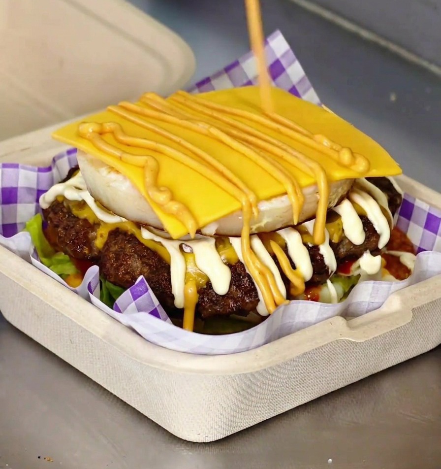 A completed gourmet burger with a visible fried egg and melted cheese tucked between toasted brioche buns.