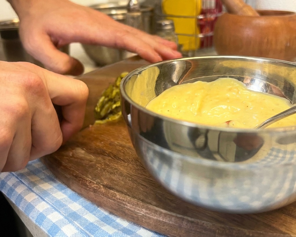 Finely diced green pickles being added to a bowl of mayonnaise, mustard, and ketchup to make a burger sauce.