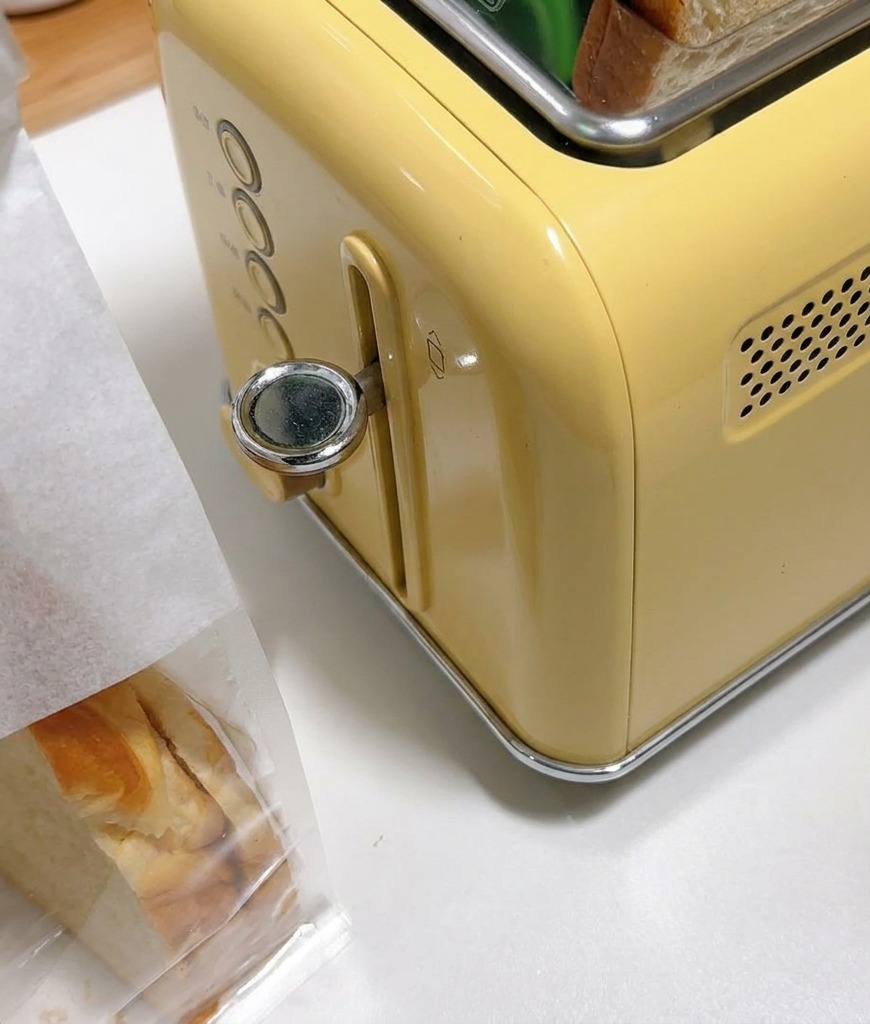 Thick slices of white bread sitting in the slots of a vintage-style yellow toaster.