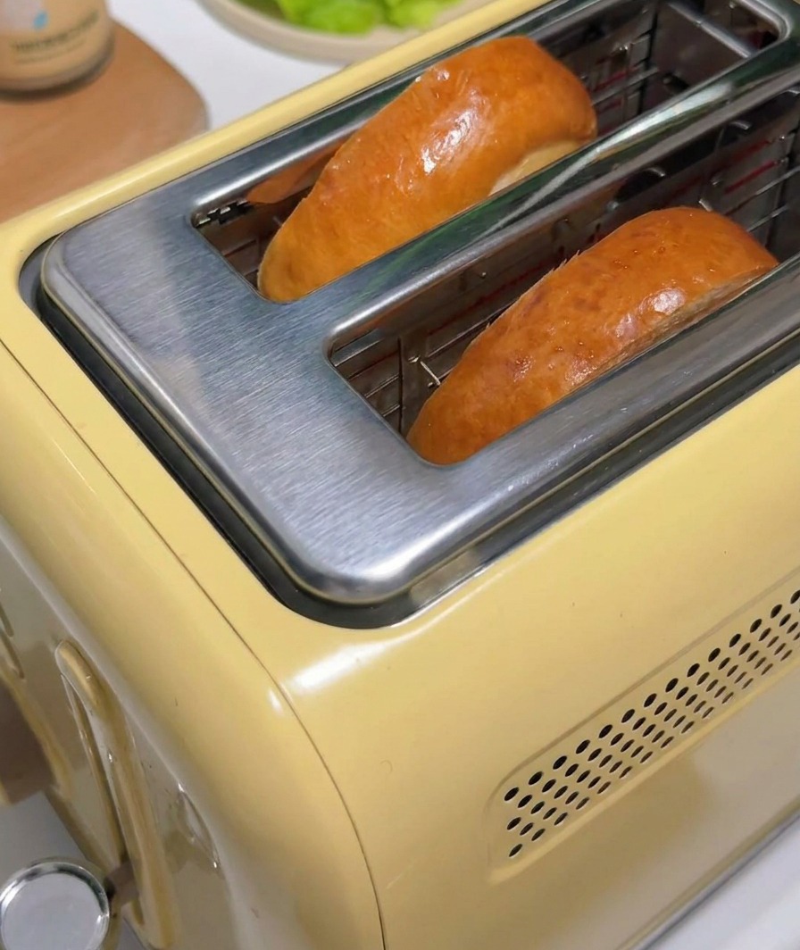 Two slices of browned toast popping up from a vintage-style yellow toaster.