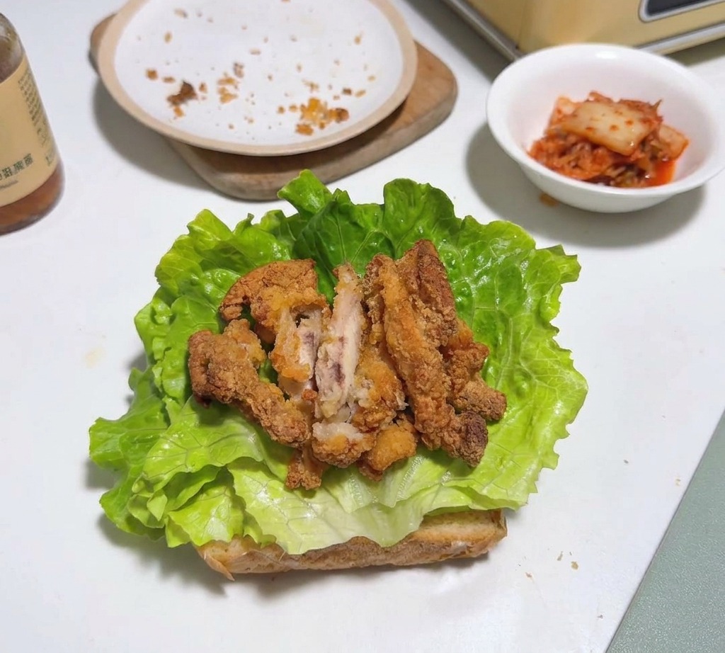 Fried chicken pieces layered on top of a lettuce leaf and toasted bread.