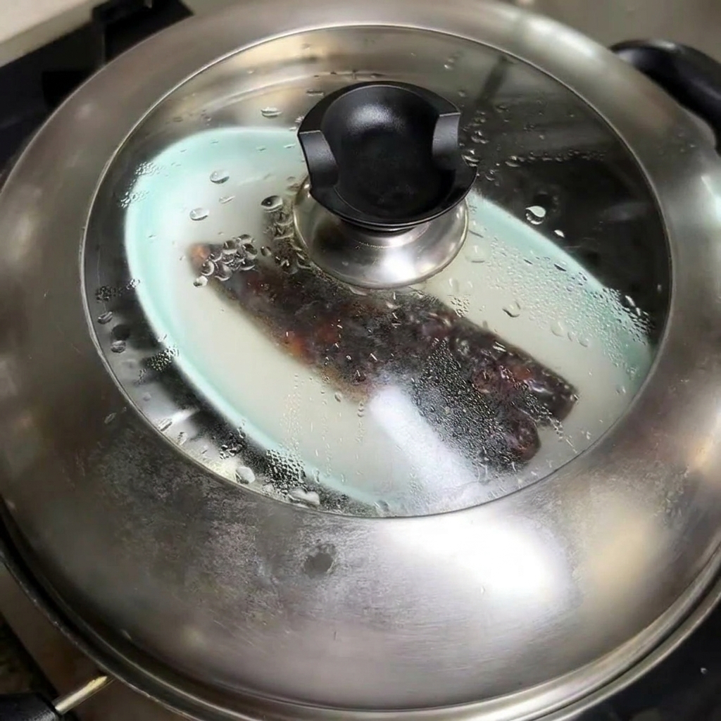Steamed Chinese sausage being cut into rounds on a wooden board.