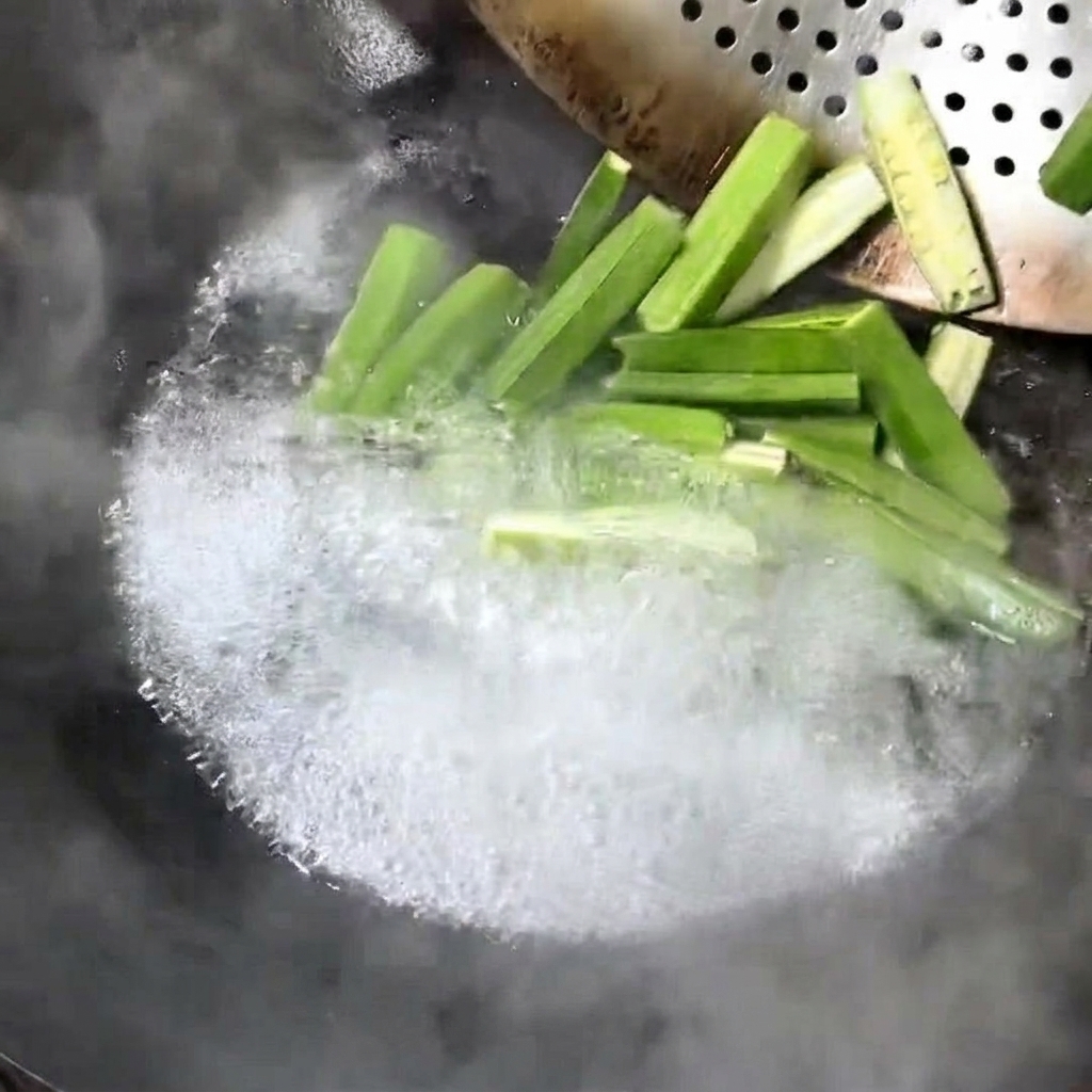 Fresh okra pieces boiling in a wok.