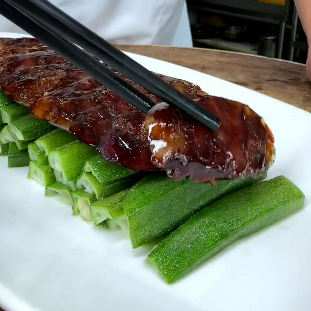Close-up of sliced Chinese sausage being laid over a bed of green okra on a white plate.