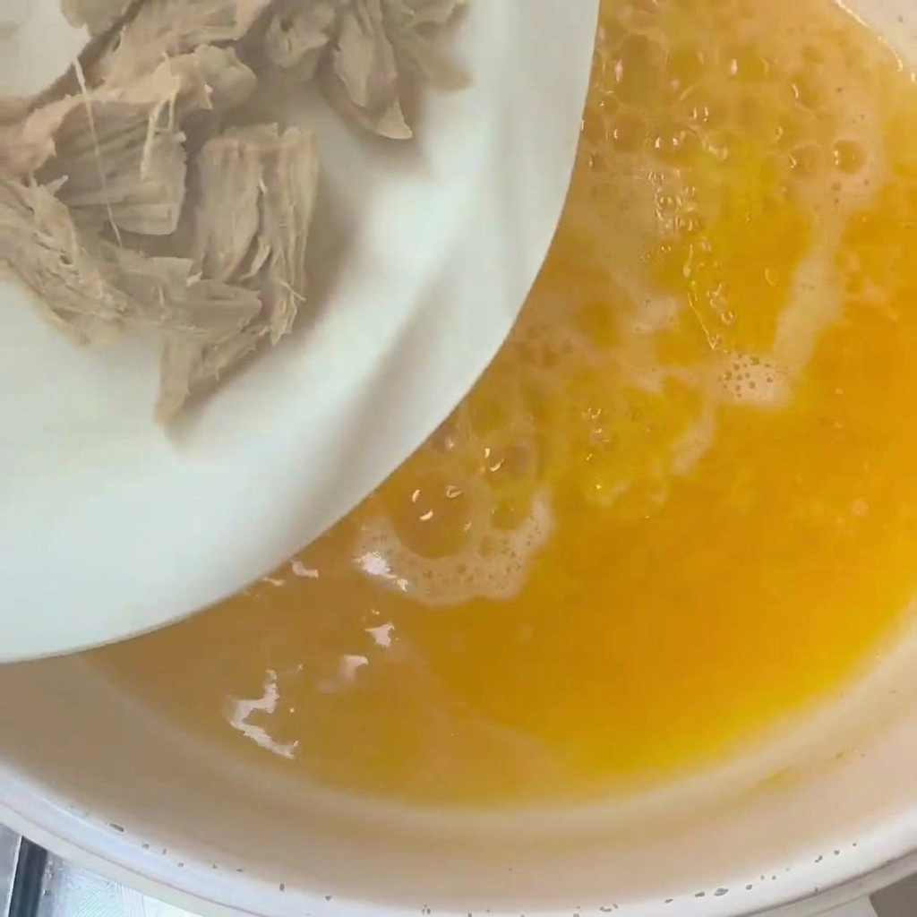 Sliced okra and duck meat being added into a pot of bubbling hot water.