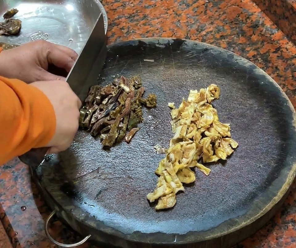 Chopped duck liver sausage and duck skin pieces arranged on a wooden cutting board.