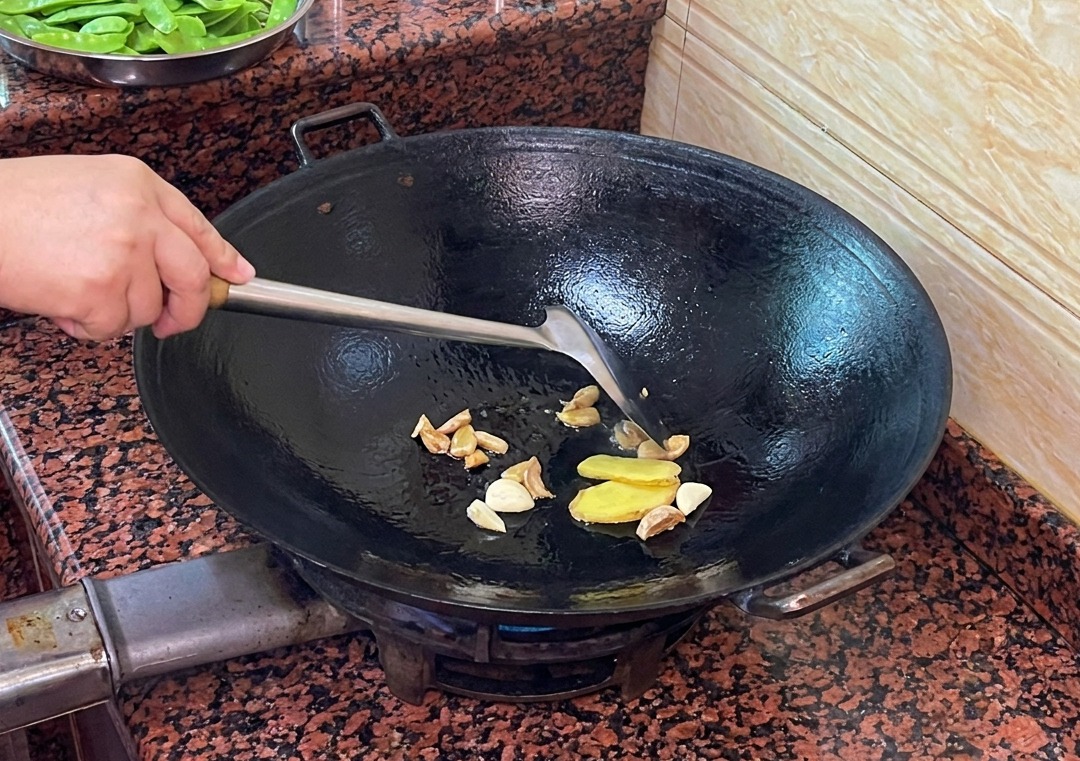 Slices of ginger and garlic sautéing in the rendered duck fat in a wok.