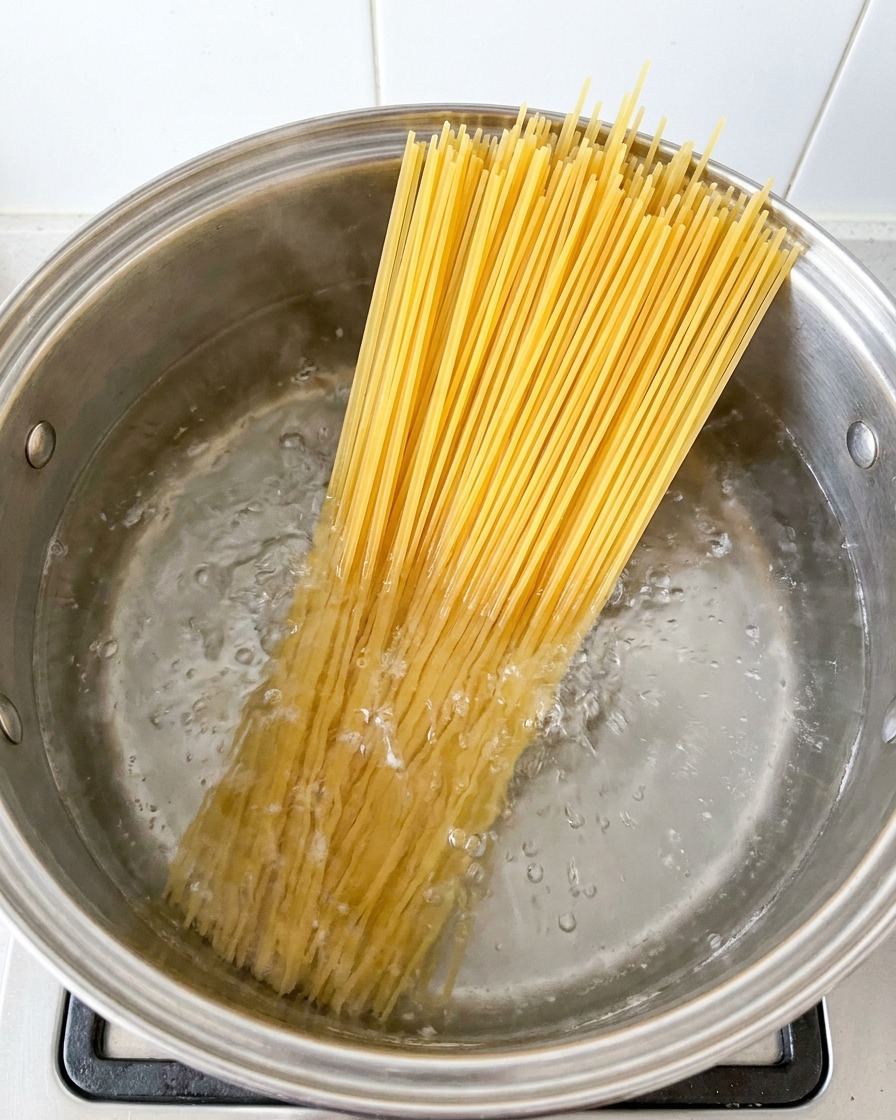 Spaghetti noodles cooking in a large pot of boiling water.