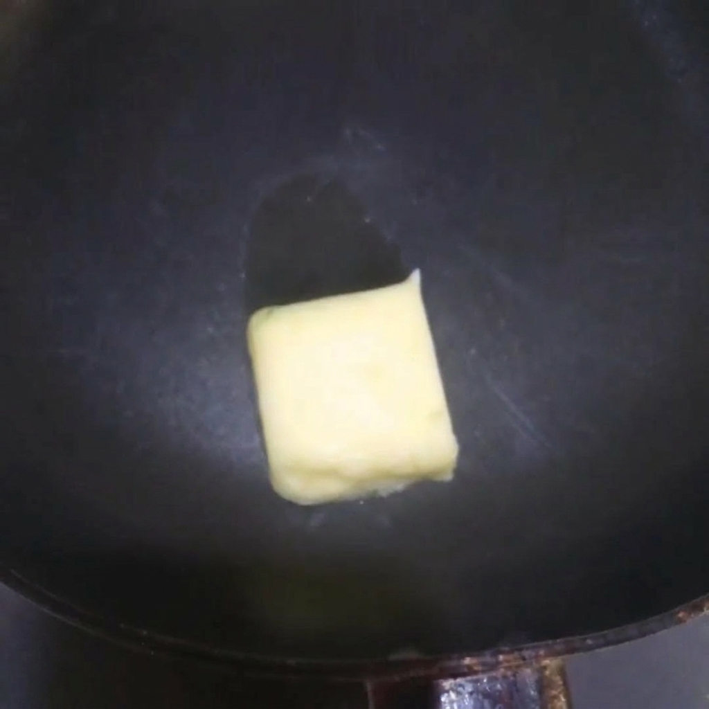 Yellow butter melting and sizzling in a hot frying pan.