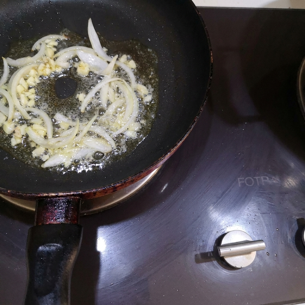 Diced onions and minced garlic being stirred into melted butter in a pan.
