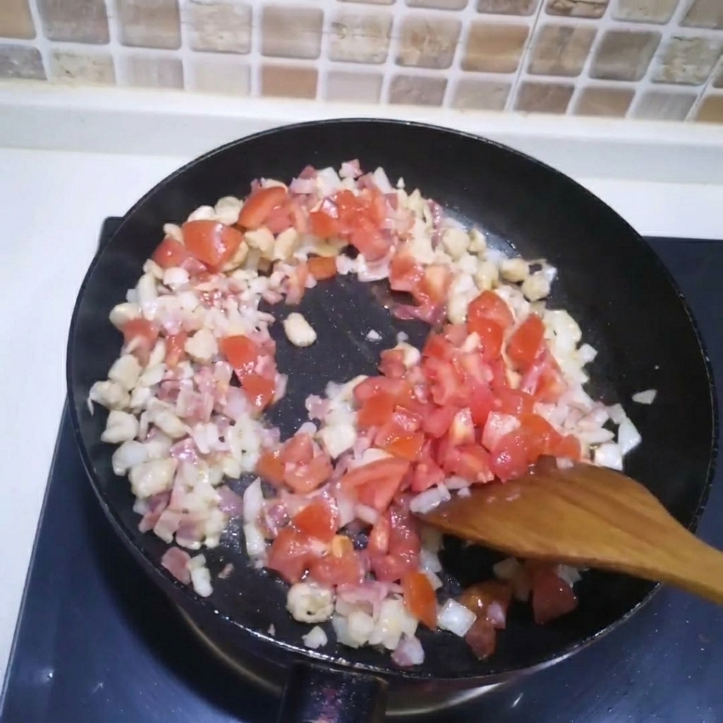 Diced tomatoes being added to a pan with stir-frying meat and onions.