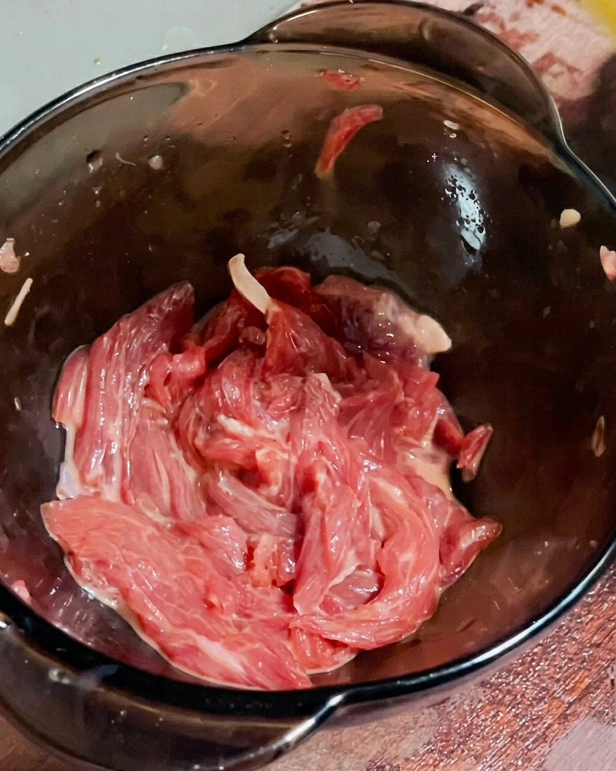 A light coating of oil being sprayed over the marinated beef mixture.