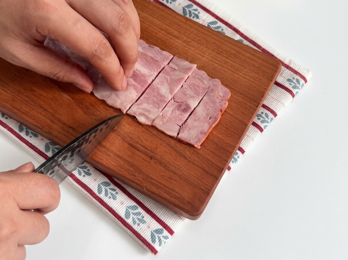 Slices of raw bacon neatly arranged on a wooden board ready for cooking.