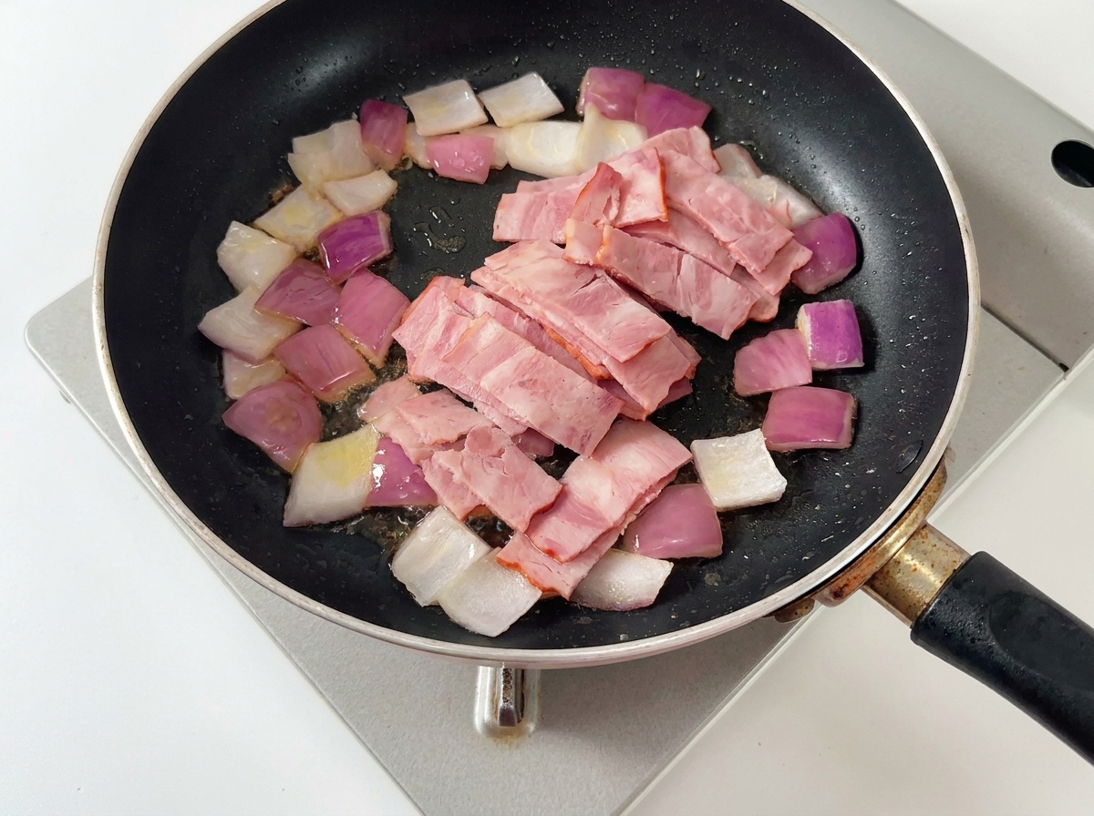 Diced onions, bacon, and mushroom slices cooking together in a buttered pan.