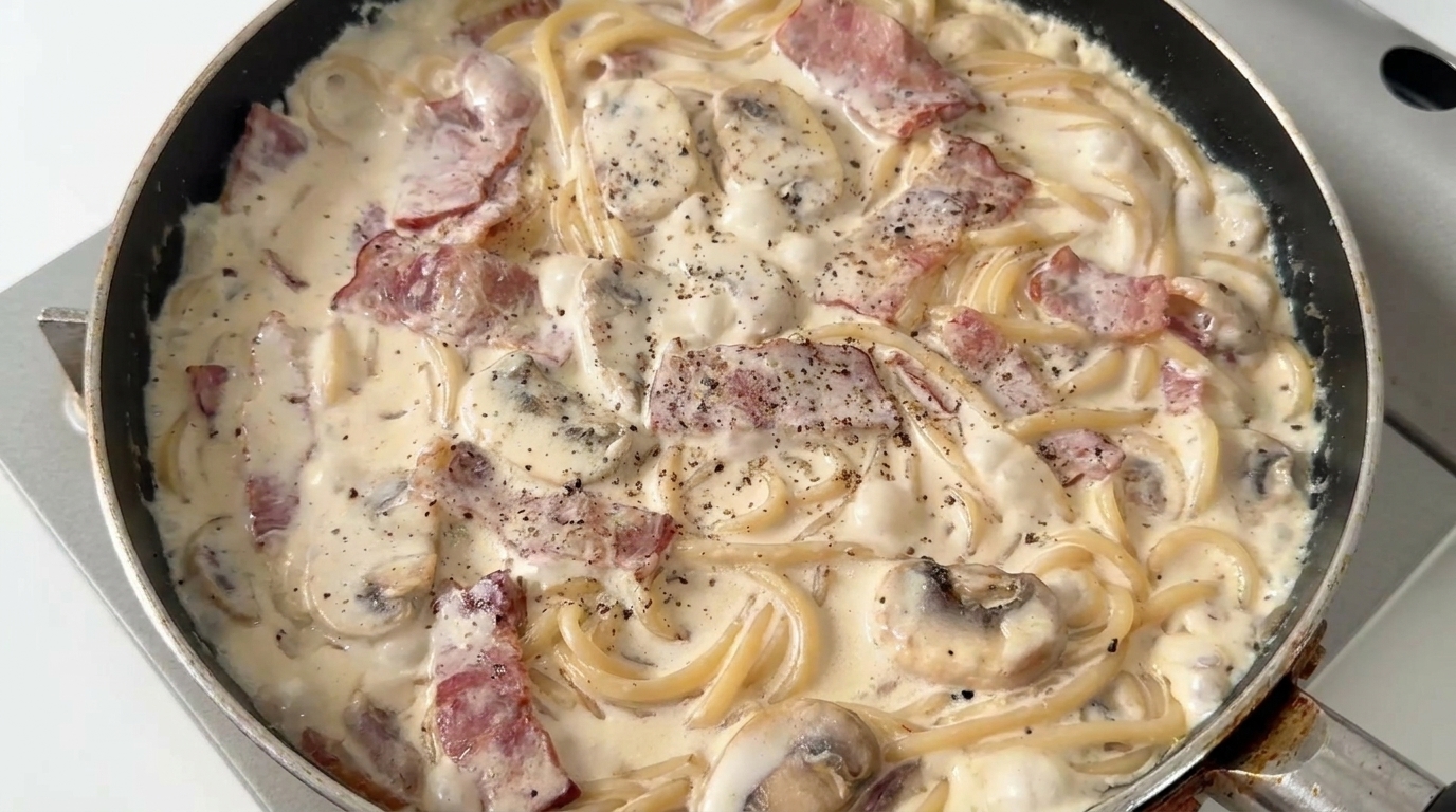 Freshly cooked creamy mushroom and bacon spaghetti, coated in a rich sauce with cracked black pepper.