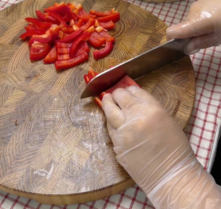 Diced red bell pepper pieces on a wooden cutting board.