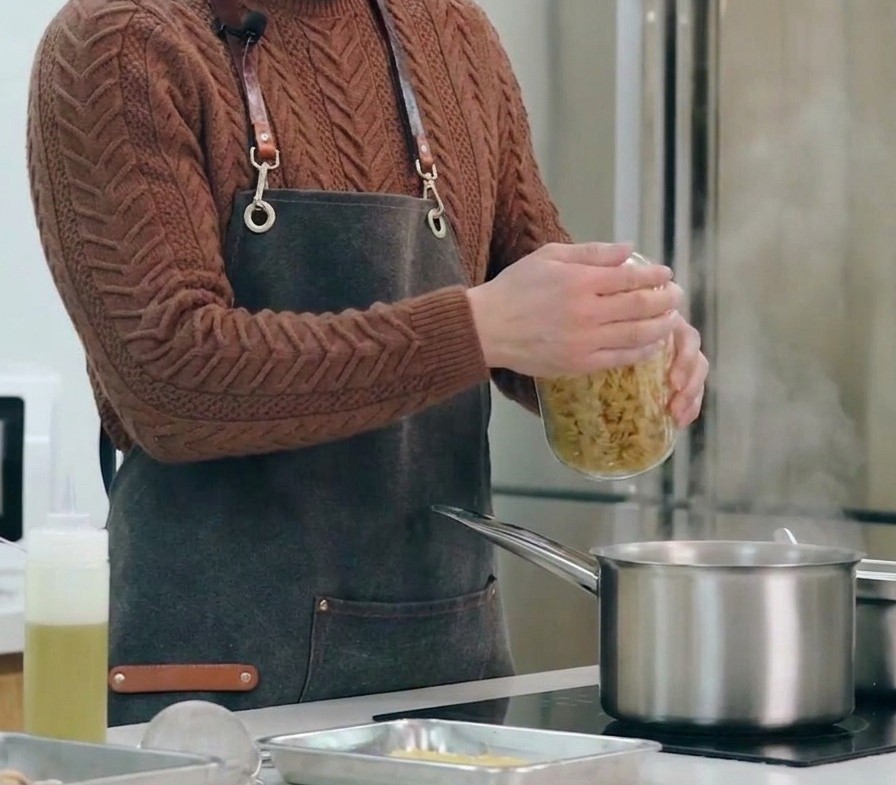 Dry spiral pasta being poured into a large pot of boiling, salted water.