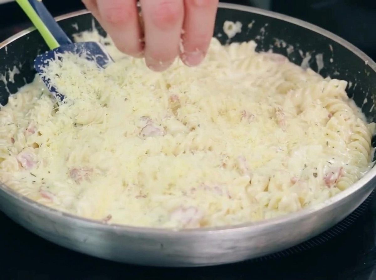 Onions and garlic cooking with bacon in a pan.