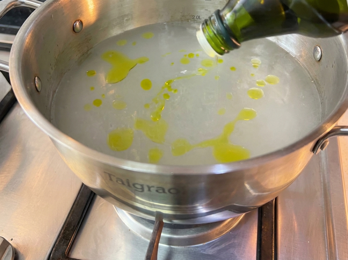 Dry spaghetti noodles submerged in a large pot of boiling water.