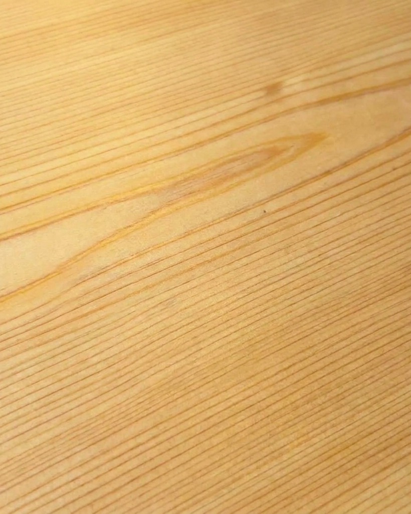 Sausage being sliced on a clean wooden cutting board.