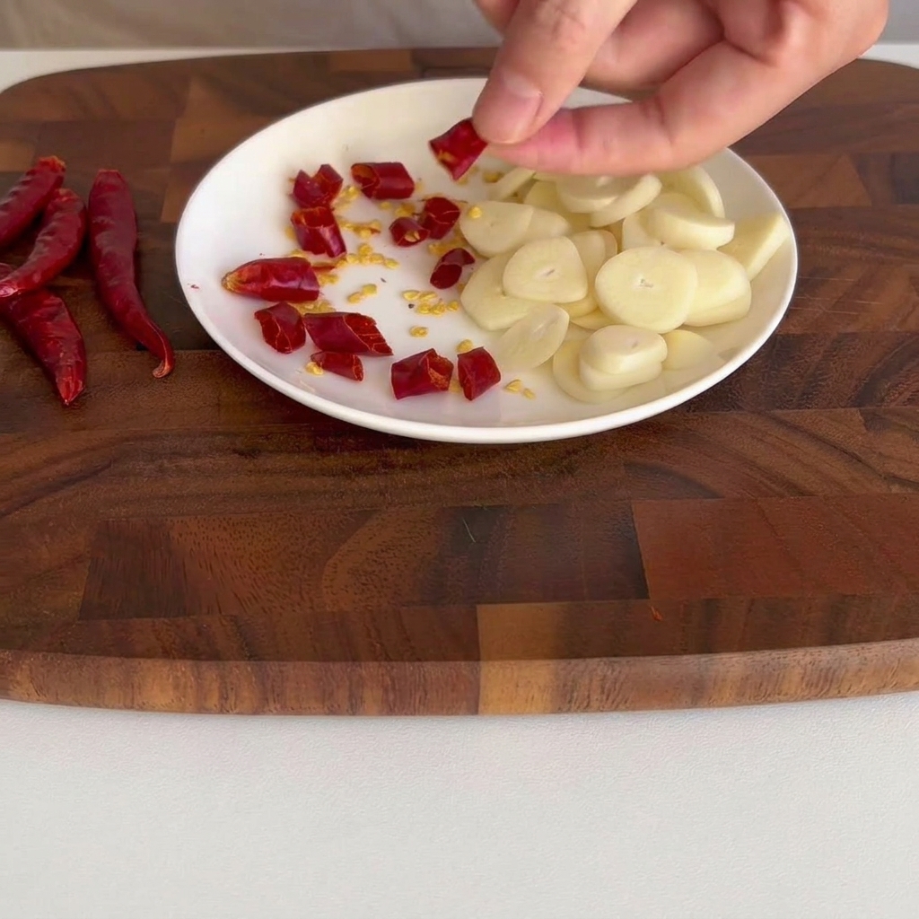 Small segments of dried red chili scattered on a small white plate.