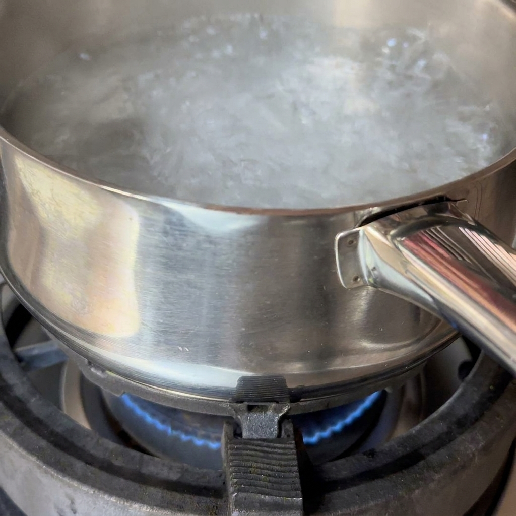 Spaghetti noodles submerged in a pot of boiling water being stirred with chopsticks.
