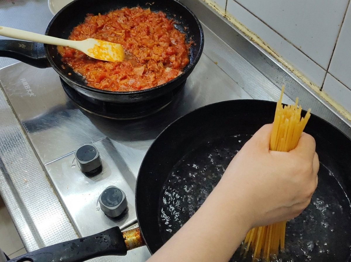 A handful of dry spaghetti being submerged into a pot of rolling boiling water.
