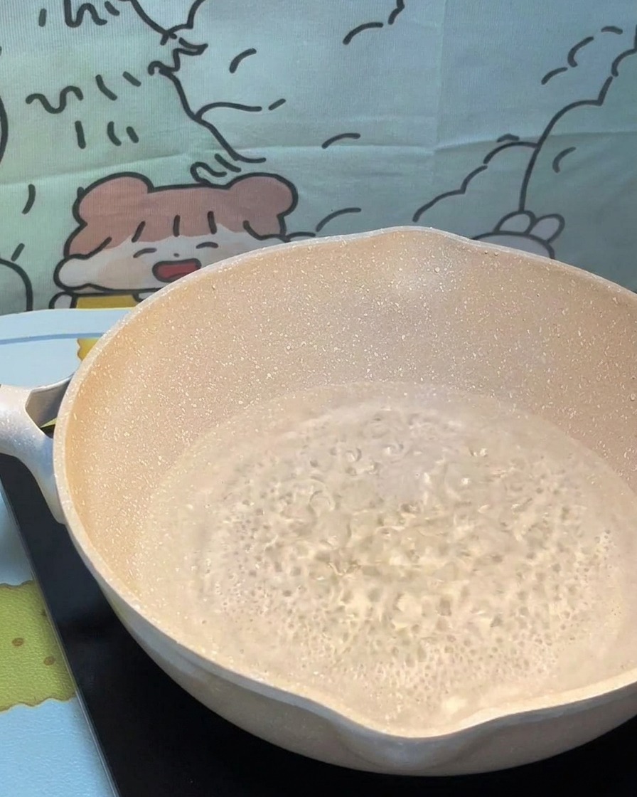 Dry pasta strands being carefully placed into a pot of bubbling boiling water.
