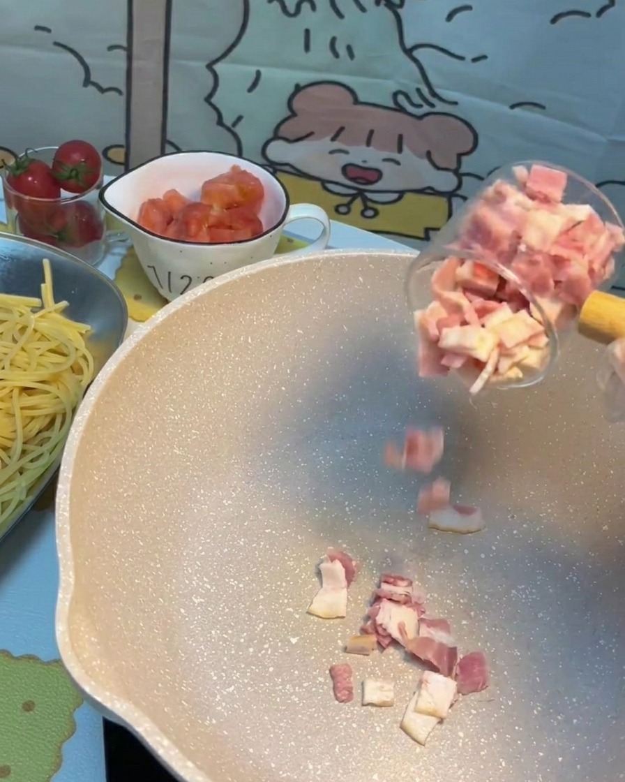 Bacon pieces sizzling and browning in a hot frying pan.