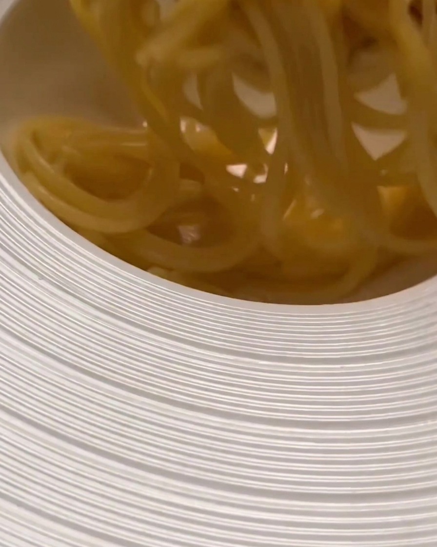Cooked pasta being transferred into a wide serving bowl, ready to be tossed with sauce.