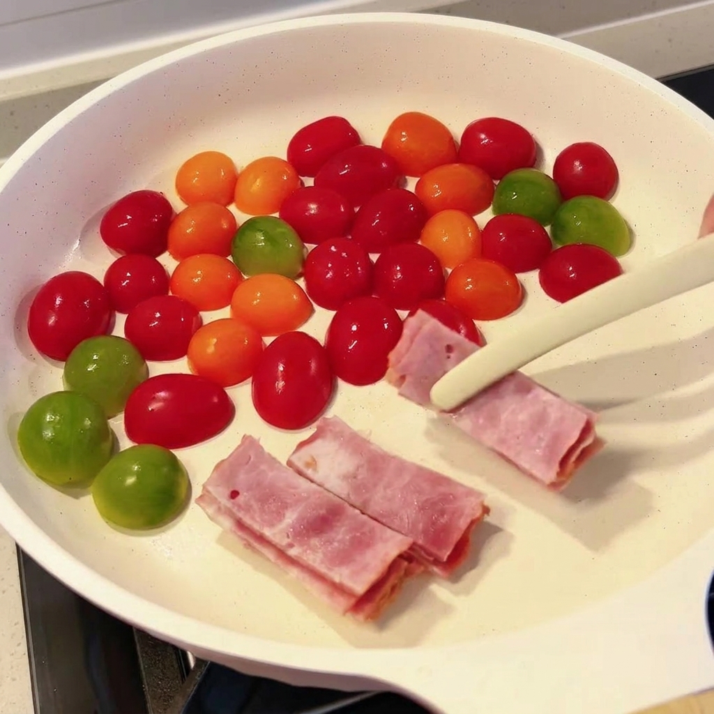 Slices of raw bacon being placed into a pan with cherry tomatoes using tongs.