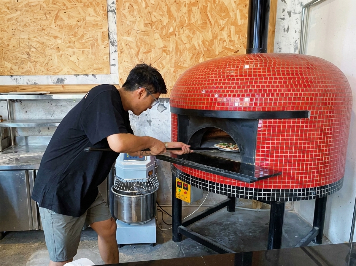 A pizza being slid into a hot wood-fired oven using a peel.