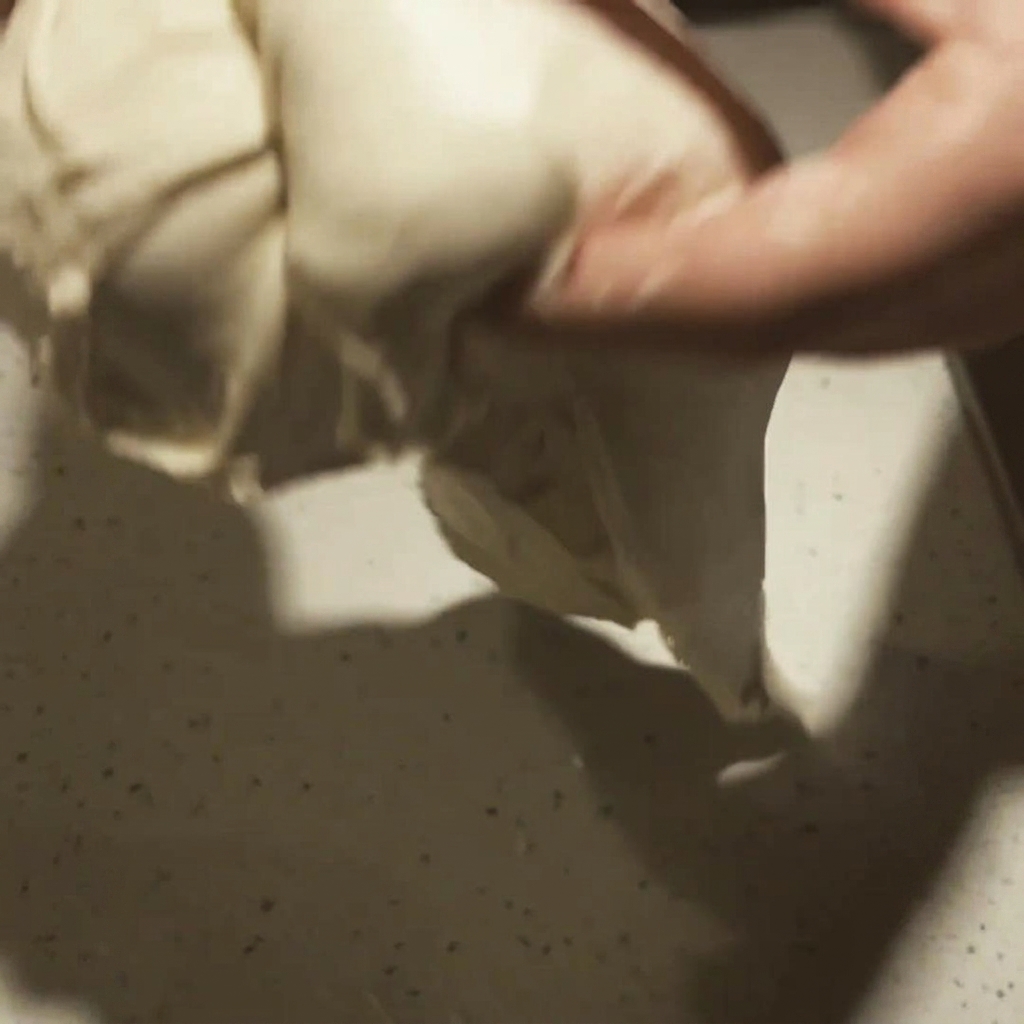 Pizza dough being stretched into a round base with a visible, puffy crust border.