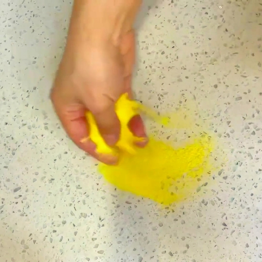 A brush applying a layer of oil to the base of a stainless steel pan.