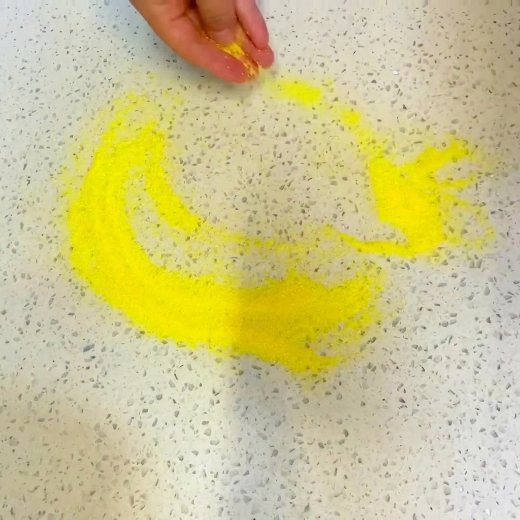 A green herb-based mint sauce being drizzled over the layer of tomato sauce on the pizza.