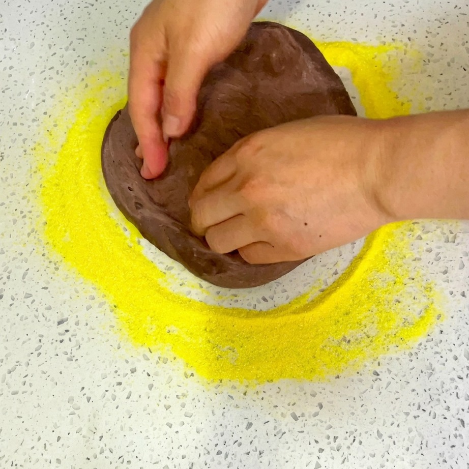 Shredded cheese being evenly sprinkled over the assembled pizza toppings.