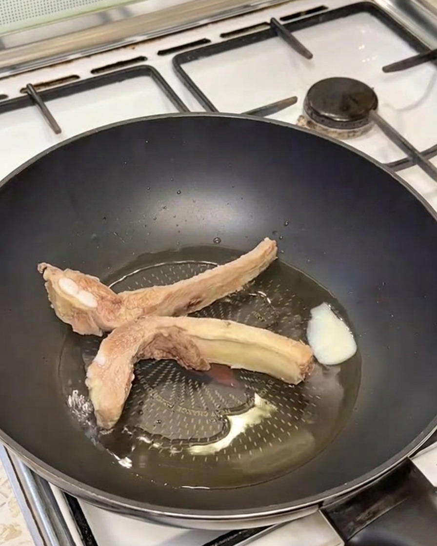 Golden-brown seared pork ribs sizzling in a pan with melted lard.