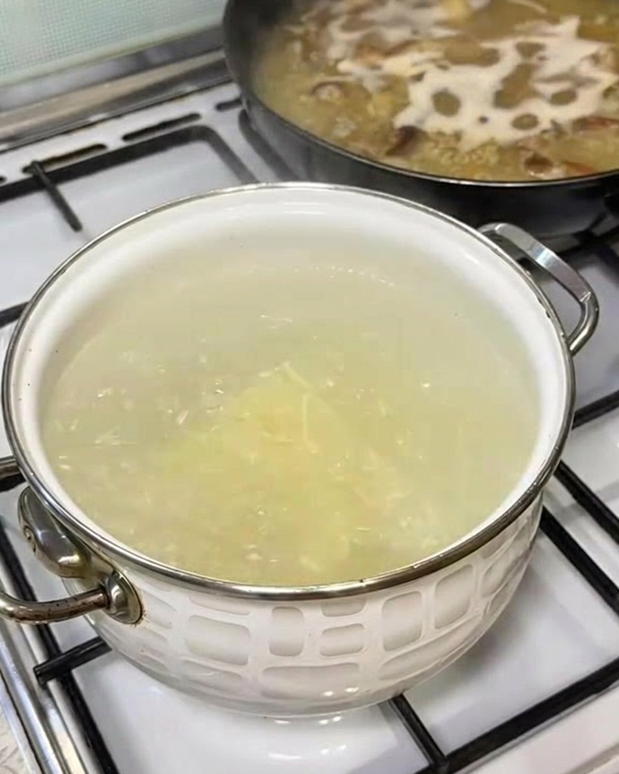 A bundle of fresh ramen noodles being dropped into a pot of boiling water.