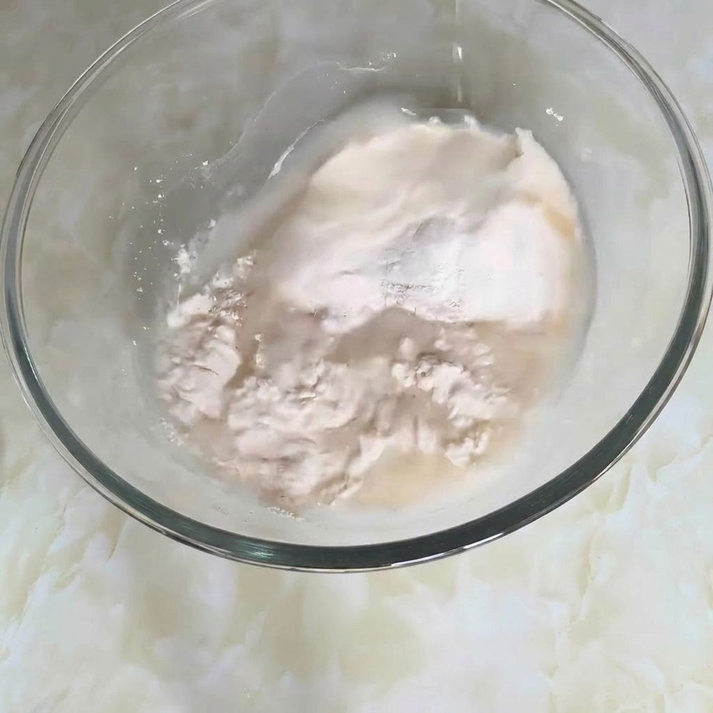 A close-up of a mixing bowl containing flour, water, and other ingredients being stirred into a dough.