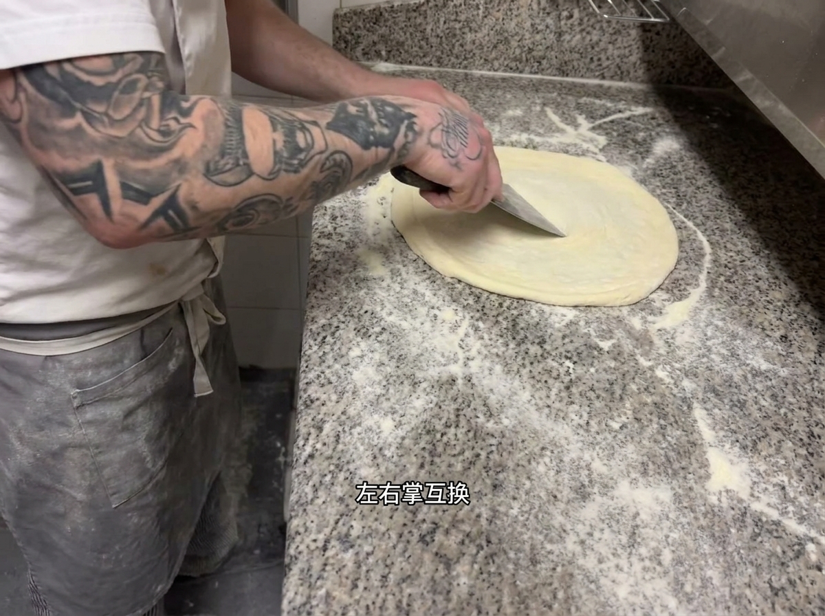 Chef performing the rhythmic stretching technique on the pizza dough.