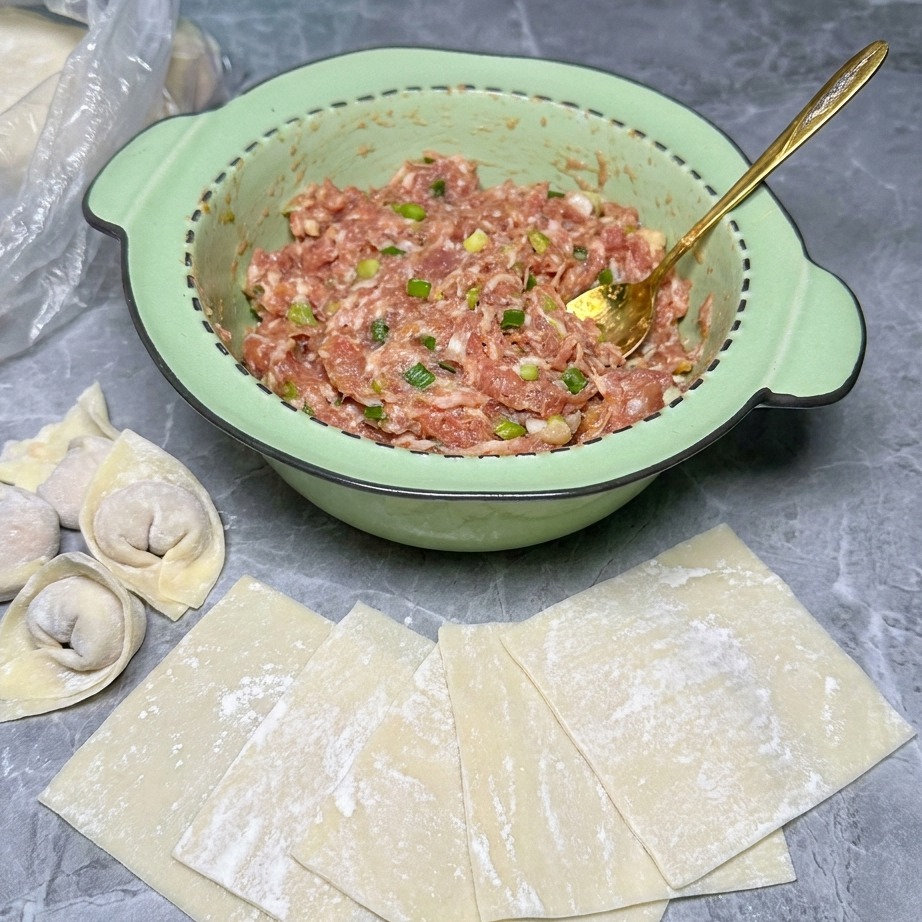 A small mound of raw meat filling sitting in the center of a square wonton wrapper.