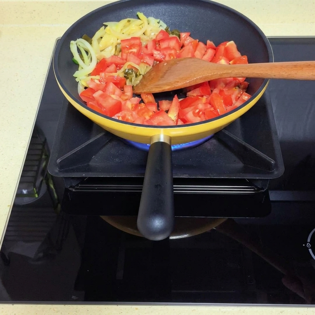 Tomatoes cooking down into a soft sauce in the pan.