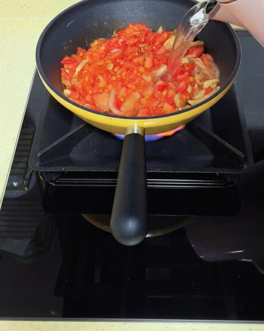 Boiling water being poured into the tomato and mustard green base.