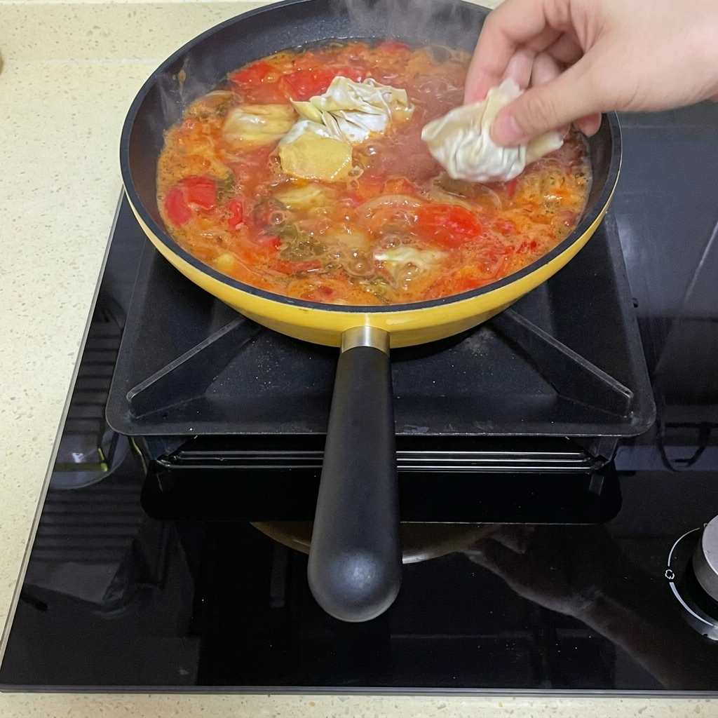 Raw folded wontons being dropped into the simmering tomato broth.